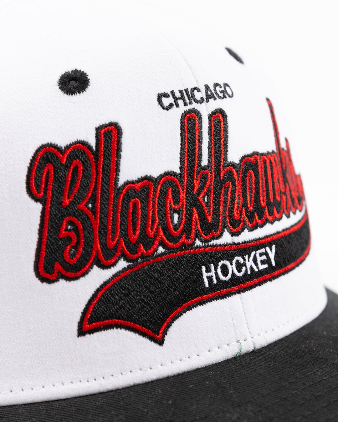 black and white Mitchell & Ness adjustable cap with embroidered Chicago Blackhawks hockey wordmark on front and primary logo on right side - front detail lay flat