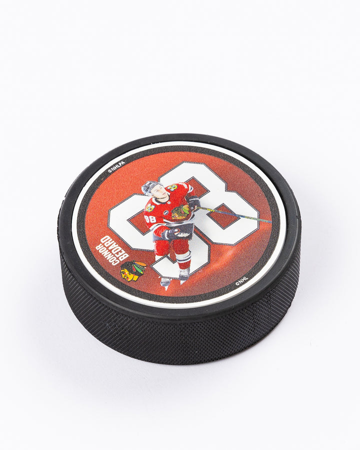 hockey puck with Connor Bedard name and number with action photo and Chicago Blackhawks primary logo - angled front lay flat