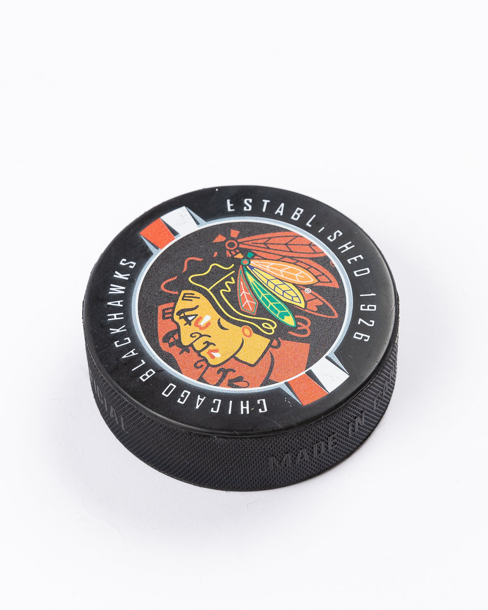 hockey puck with Chicago Blackhawks primary logo and ribbon-inspired design - front angled lay flat