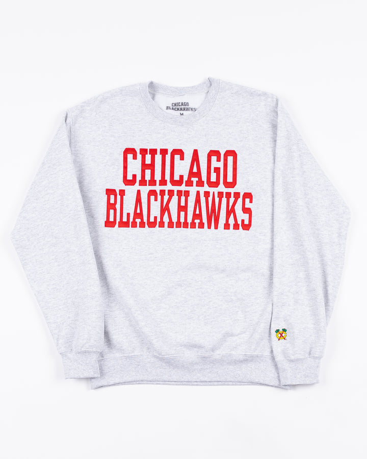 light grey crewneck sweatshirt with Chicago Blackhawks wordmark in red across front and Chicago Blackhawks secondary logo on left cuff - front lay flat