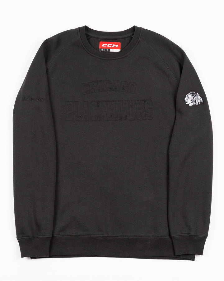 black CCM crewneck sweater with tonal Chicago Blackhawks wordmark across front and black and white primary logo embroidered on left shoulder - front lay flat