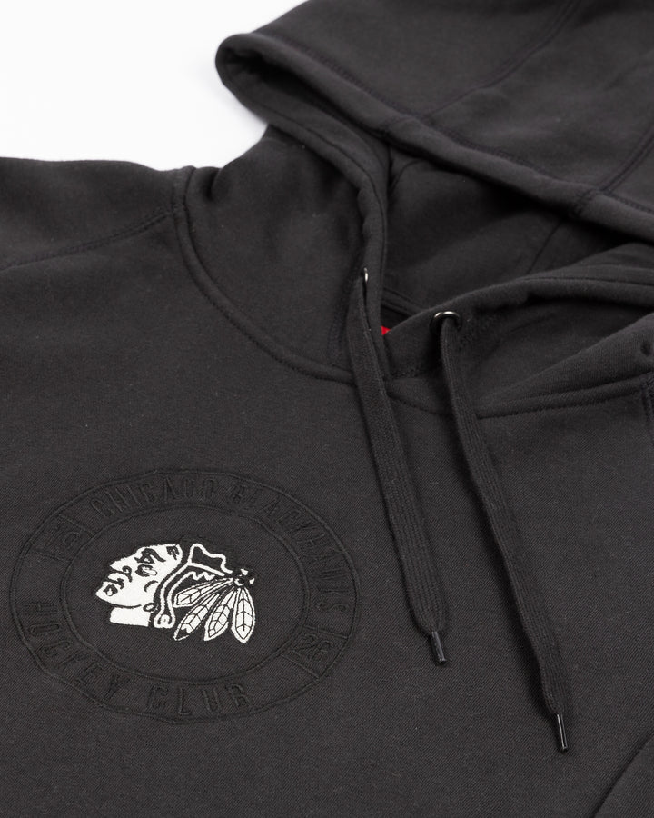 black CCM hoodie with Chicago Blackhawks black and white primary logo on front surrounded by tonal wordmark logo - front detail lay flat