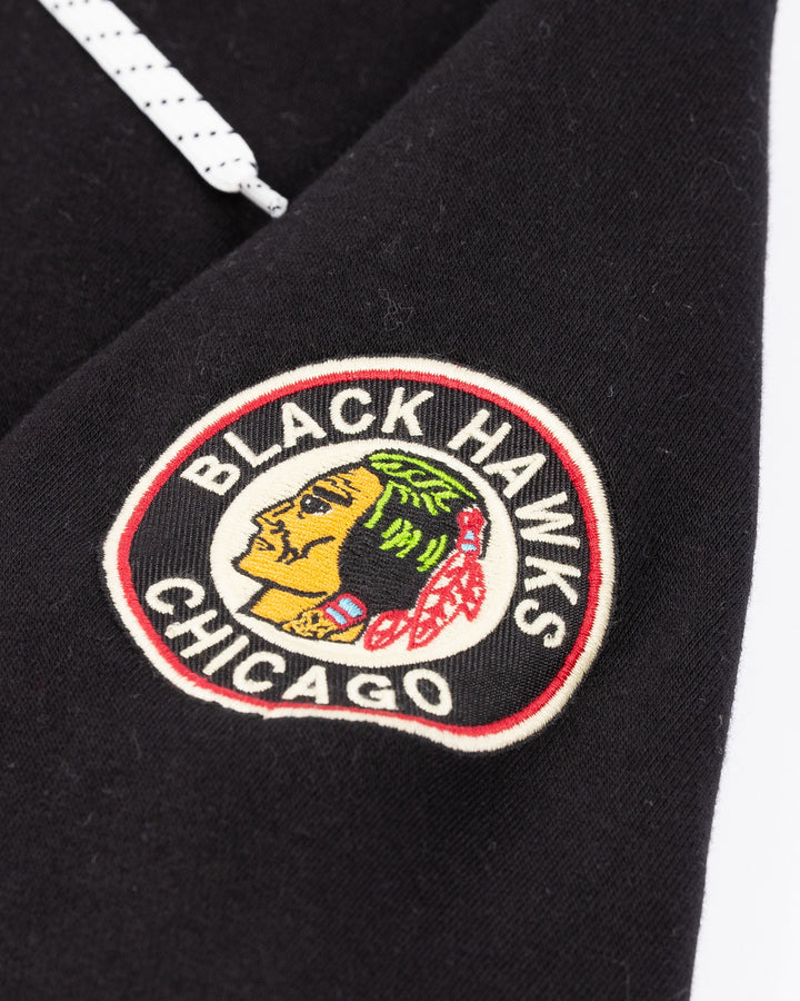 black CCM lacer hoodie with red Chicago Blackhawks wordmark across front and vintage Chicago Blackhawks logo on left shoulder - shoulder detail lay flat