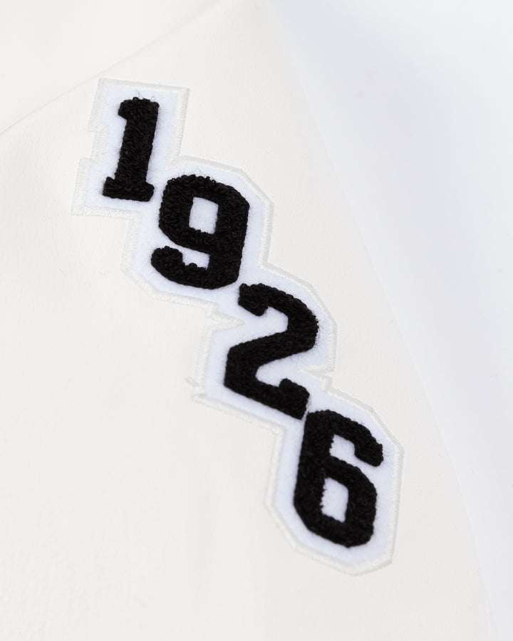 black and white CCM varsity jacket with Chicago Blackhawks primary logo on right shoulder and CCM logo embroidered on right chest and CB patch on left chest and 1926 embroidered on left shoulder - 1926 detail lay flat