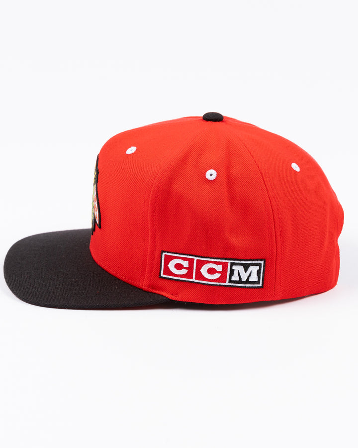 two tone red and black CCM flat brim hat with Chicago Blackhawks primary logo embroidered on front and CCM logo on left side - left side lay flat