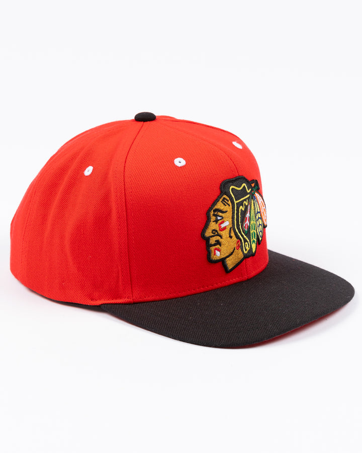 two tone red and black CCM flat brim hat with Chicago Blackhawks primary logo embroidered on front and CCM logo on left side - right angle lay flat