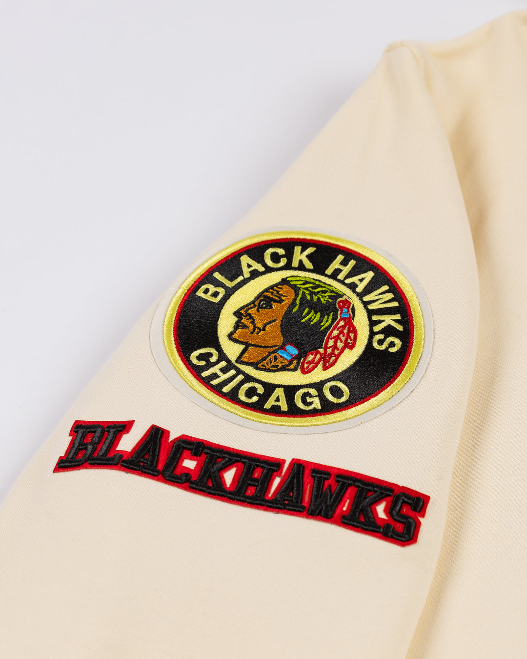 cream Pro Standard hoodie with black striping on hem and cuffs and vintage Chicago Blackhawks logo patches on front, hood and shoulders - shoulder detail lay flat