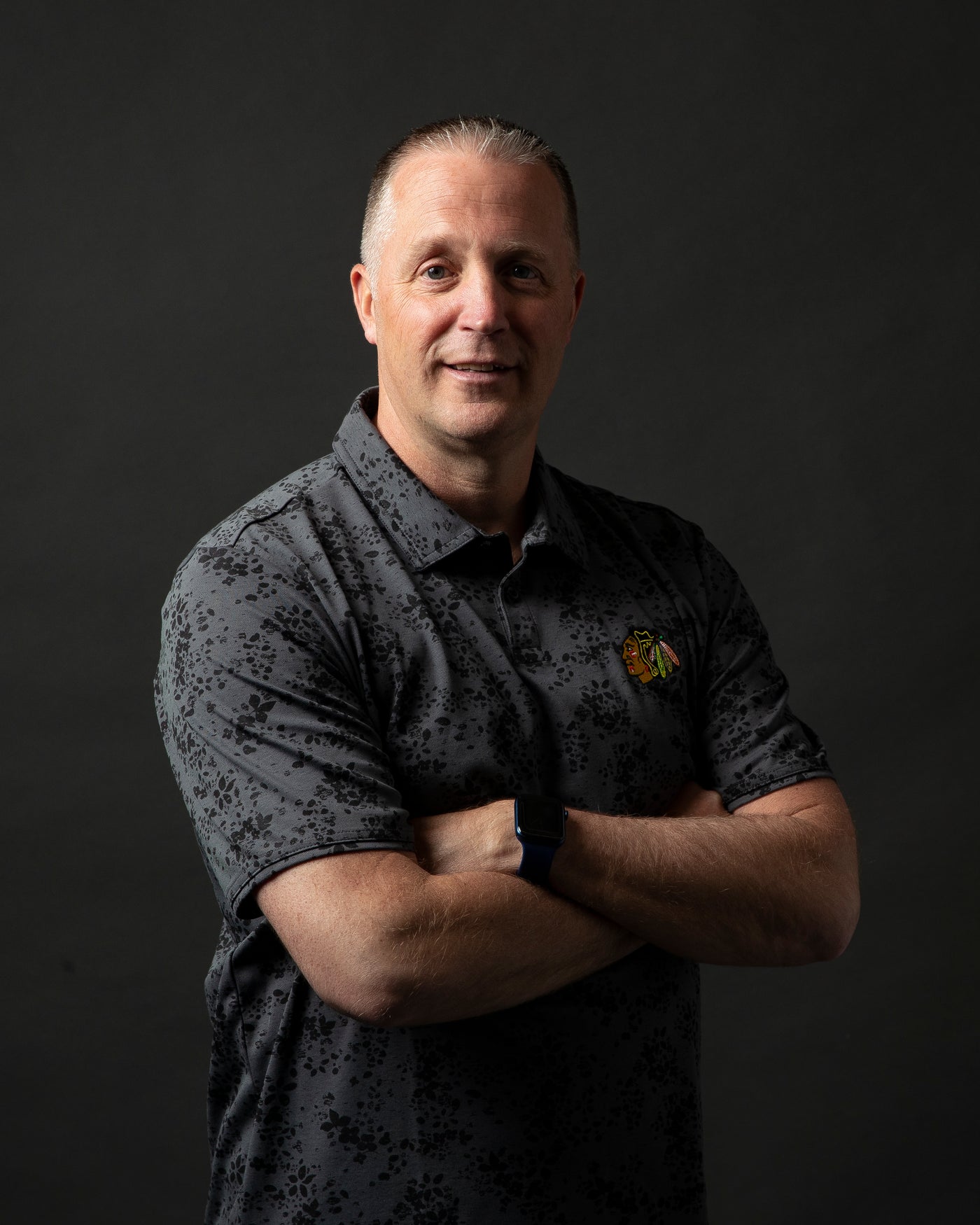 black floral print TravisMathew polo with embroidered Chicago Blackhawks primary logo embroidered on left chest - on Mike Doneghey Director of Amateur Scouting for the Chicago Blackhawks