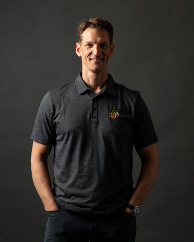 dark grey TravisMathew polo with button closure and embroidered Chicago Blackhawks primary logo on left chest - on Mark Eaton, Assistant GM Player Development for the Chicago Blackhawks 