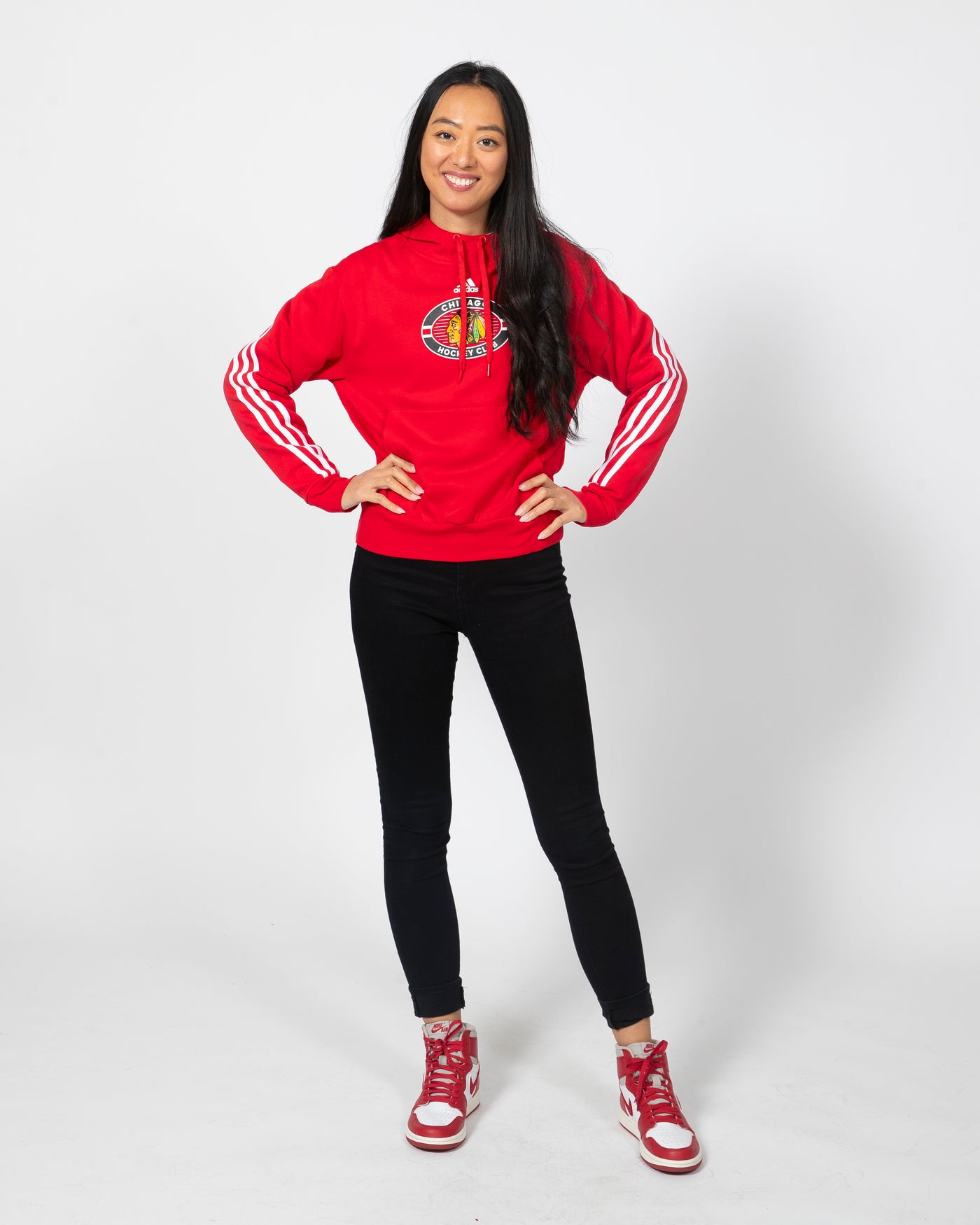 Red adidas hoodie with primary logo on center chest and three white stripes going down both arms - front view on model
