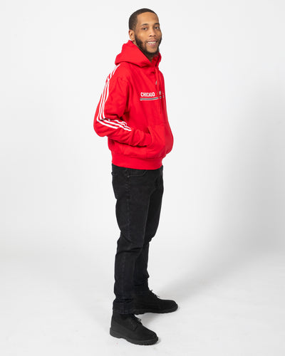 Red adidas hoodie with primary logo and wordmark graphic with three white stripes down sleeves - on model alt side view