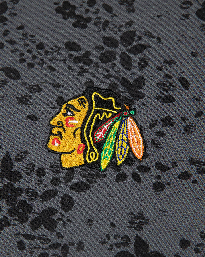 black floral print TravisMathew polo with embroidered Chicago Blackhawks primary logo embroidered on left chest - detail lay flat