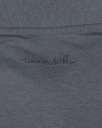 black TravisMathew polo with embroidered tonal primary logo on left shoulder - logo detail lay flat