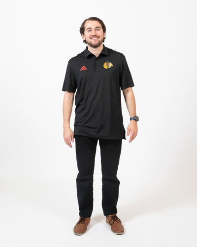 Black adidas polo with embroidered primary logo on left chest and red embroidered adidas logo on right chest - front on model shot