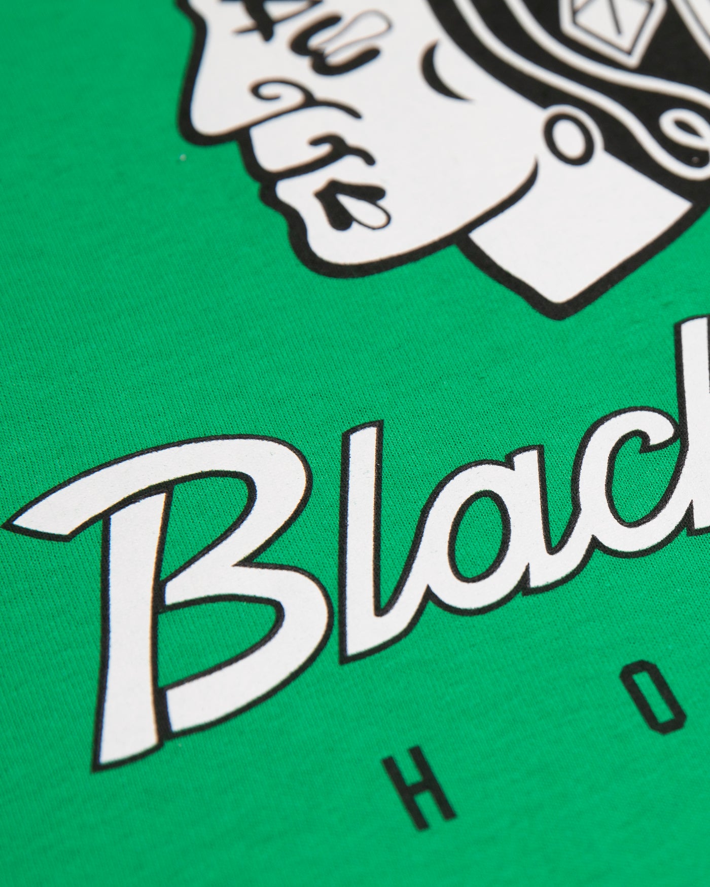 Green Chicago Blackhawks tee with black and white tonal primary logo and wordmark across chest - front lay flatGreen Chicago Blackhawks tee with black and white tonal primary logo and wordmark across chest - alt detail lay flat